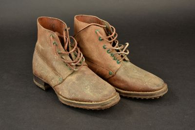 pair of brown leather boots with green laces on a black background