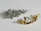 pair of gold and silver brooches on a white surface