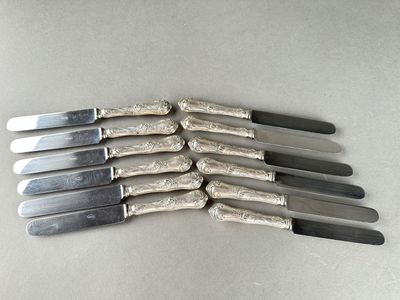 six couteaux en métal argenté sont alignés sur une table