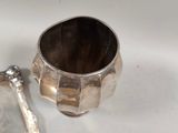a silver spoon and a silver cup on a table