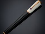 a black and white pen with gold accents on a black background