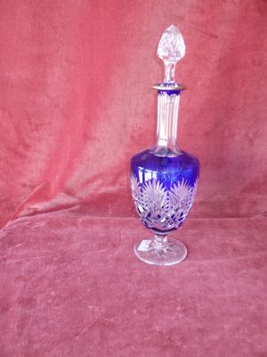 un vase en verre bleu avec un couvercle transparent, posé sur un tissu rouge