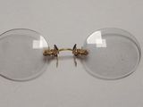 une paire de verres transparents à monture dorée posés sur une surface blanche