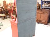 a tall dresser with a red top in a room