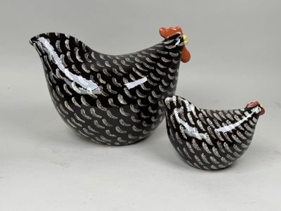 deux poulets en céramique, l'un noir et l'autre blanc, assis l'un à côté de l'autre