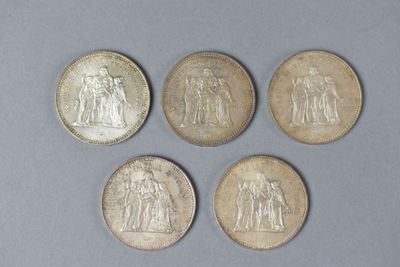 four different types of silver coins on a gray surface