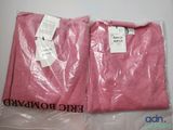 Deux t-shirts roses sont emballés dans des sacs en plastique sur une table