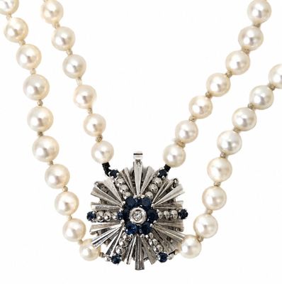a close up of a necklace with pearls and a flower