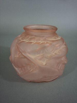 un vase en verre rose orné d'un motif de feuilles