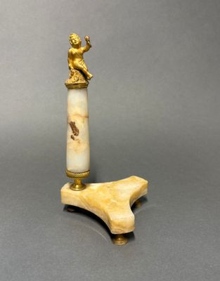 une petite figurine en ivoire posée sur un socle en bois, surmontée d'une autre figurine