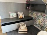 a teddy bear sitting on a shelf in the corner of a room