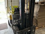 un chariot élévateur dans un entrepôt, avec des piles de bois en arrière-plan