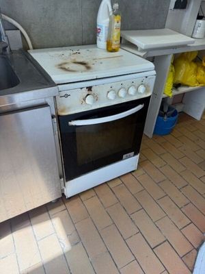 a dirty stove and sink in a dirty kitchen