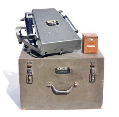 une valise sur laquelle est posée un appareil photo, posée sur une surface blanche