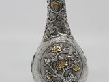 silver and gold vase with a dragon design on it