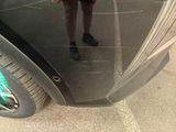 a woman standing in front of a car with a cell phone in her hand