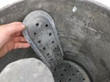 a person holding a metal bucket with holes in it