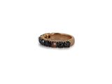 a close up of a ring with black stones on a white background