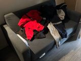 a black couch with a bunch of clothes on it