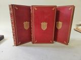 three red books with gold trim and a crown on top of them