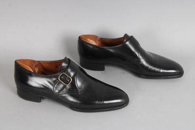 une paire de chaussures en cuir noir avec une boucle dorée