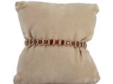 beige pillow with a cushion and a gold bracelet on it