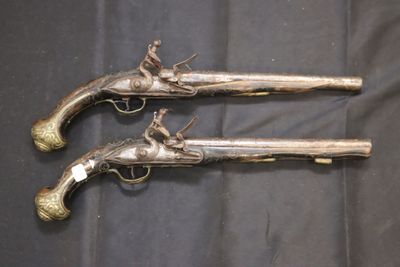 paire de pistolets anciens plaqués argent, posés sur un tissu noir