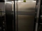 un grand réfrigérateur en inox dans une cuisine dotée de nombreux plans de travail