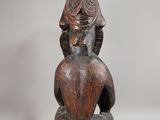 an image of a wooden statue of a woman sitting on a stool