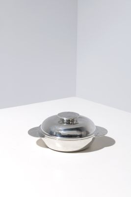 a silver bowl with a lid sitting on a white table