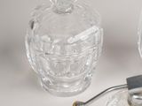 a glass bottle with a metal handle next to a glass jar with a flower on it