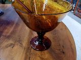 un saladier en verre posé sur une table en bois, avec une cuillère à l'intérieur
