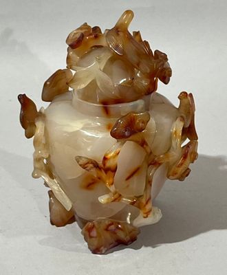 un vase blanc orné de fleurs marron, posé sur un fond blanc