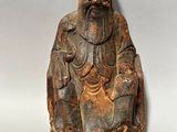 une vieille statue en bois représentant un homme barbu coiffé d'un chapeau