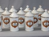seven white canisters with gold trim on them on a table