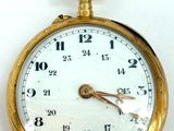 a close up of a gold pocket watch on a white surface