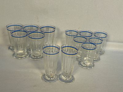 six verres transparents aux bords bleus sont alignés sur une surface blanche