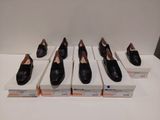 six paires de chaussures noires sont alignées sur une table blanche