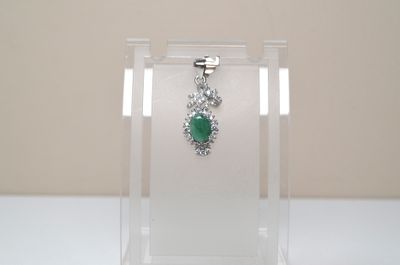 a necklace with a green stone on it in a clear display case