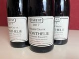 three bottles of wine sitting on a counter in front of a red wall