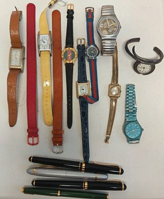 de nombreux modèles différents de montres et de stylos disposés sur une table