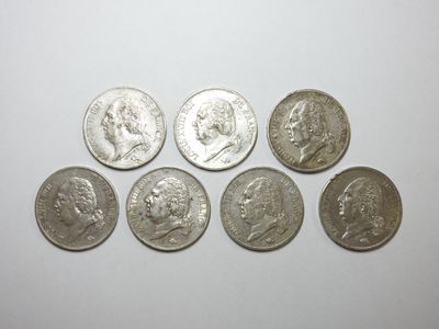 un groupe de cinq pièces d'argent posées sur une surface blanche