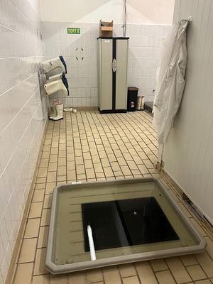 un trou dans le sol d'une salle de bains équipée de toilettes