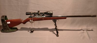 un vieux fusil avec une lunette de visée sur un support sur fond blanc