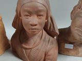 three clay heads of a woman and a cat on a table