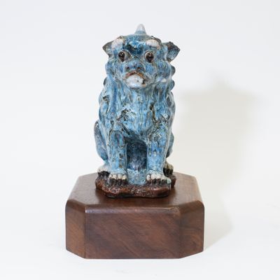 statue d'un chien bleu sur un socle en bois, sur fond blanc