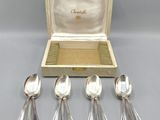 a set of five silver spoons in a case