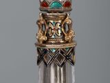 a glass bottle with a gold and green decoration on it