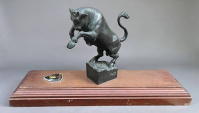 bronze statue of a lion on a wooden base on a gray background