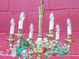 un lustre doré orné de feuilles vertes et de bougies suspendues
